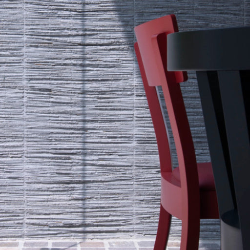 Roter und schwarzer Retro Beizenstuhl Bergamo an einem Tisch vor grauer Wand stilvolles Moodbild für Gastronomie und Café