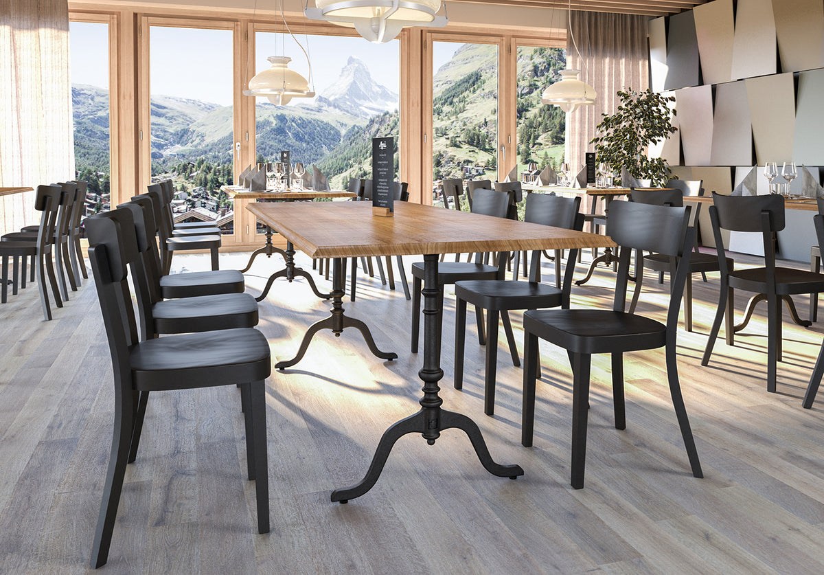 Helles Restaurant mit grossen Fenstern Blick aufs Matterhorn Holztische mit Gusseisenfuss und schwarze Stühle in moderner Einrichtung